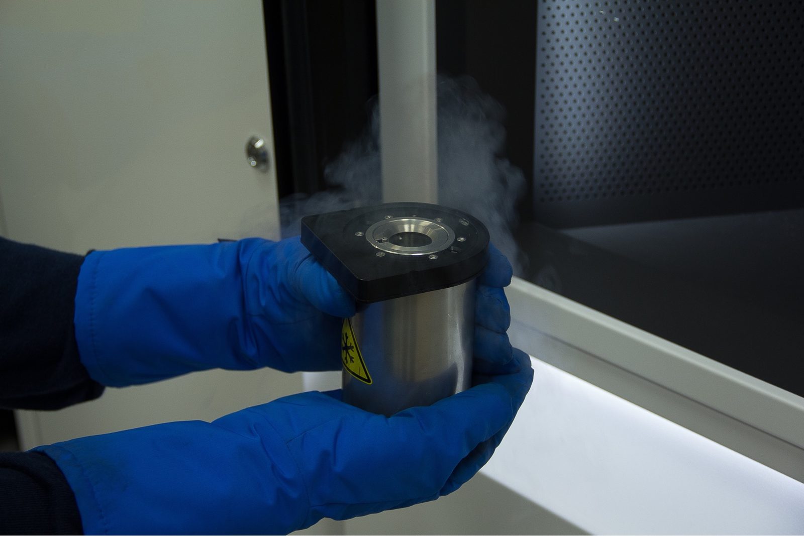 Gloved hands holding a liquid-nitrogen grid transfer station